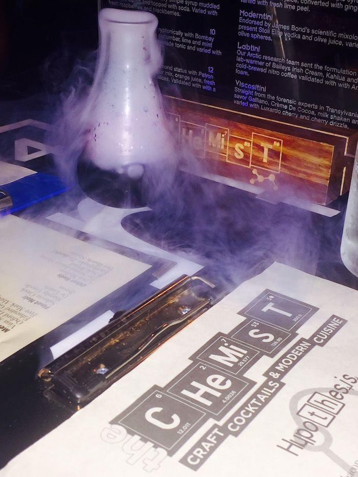 The Chemist menu and a smoking cocktail in a beaker