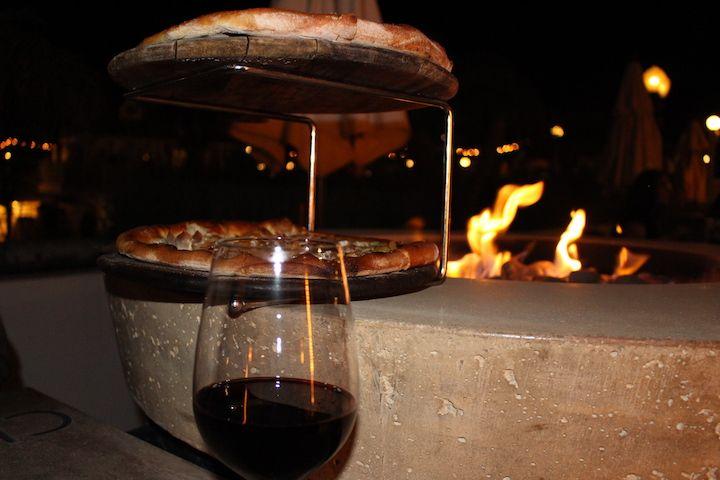 pizzas on a pizza stand by a fire pit