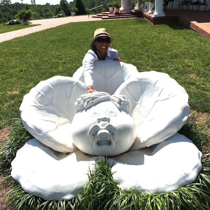 a woman standing near a Cabbage Patch doll statue