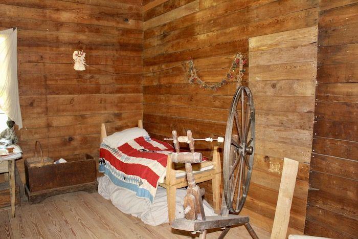 a bed and spinning wheel inside the slave cabin