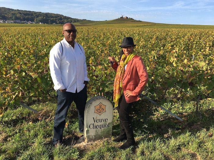 the author and her husband in a winery by a Veuve Clicquot sign