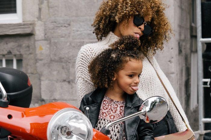 woman and female child on motor bike sticking out tongues