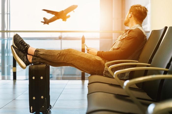 male traveler at airport watching plane take off