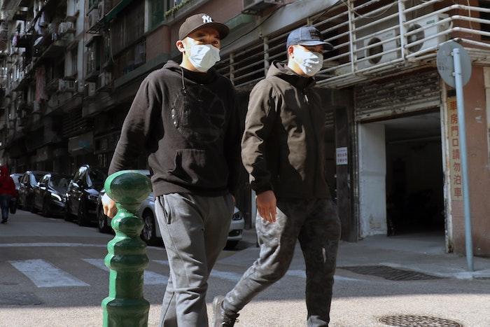 two men wearing face masks on the street