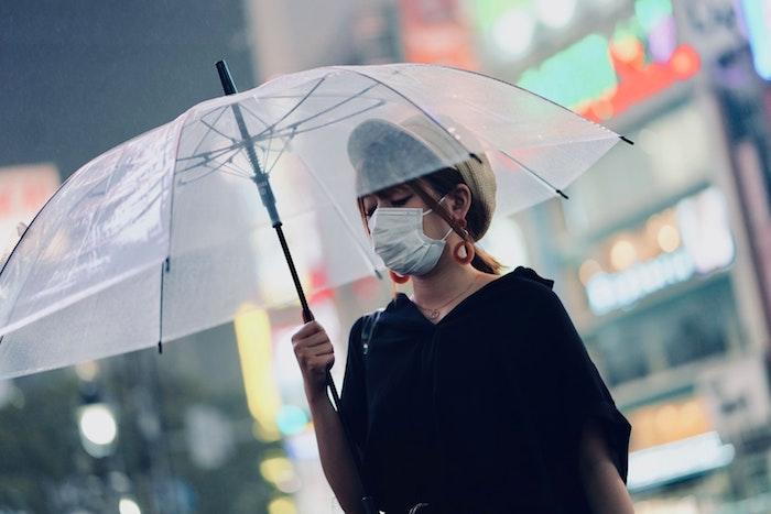 woman under umbrella with mask on