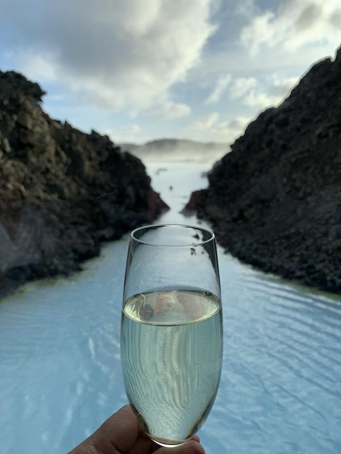 a glass of champagne held up against the Blue Lagoon