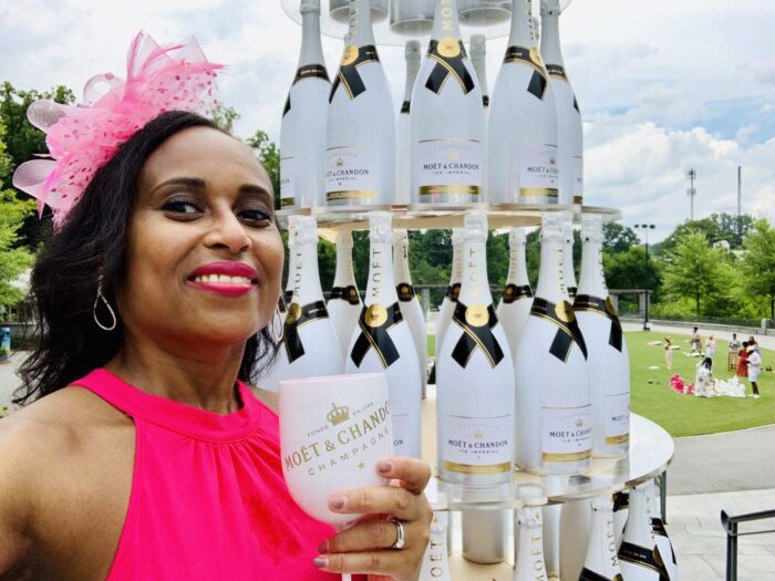 Nadeen with a Moet & Chandon Rosé Imperial Champagne glass in front of a tower of wine bottles