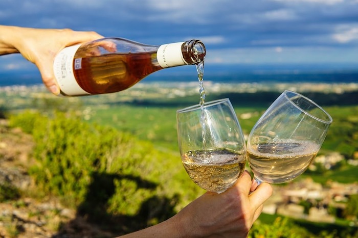 rosé wine being poured from a bottle into two glasses