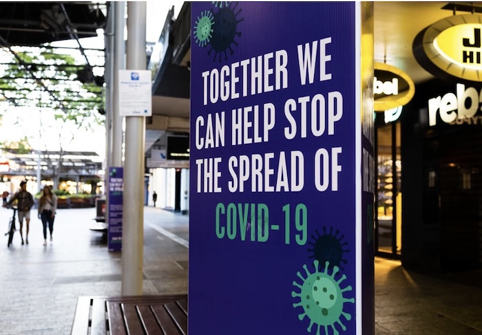 Sign in an outdoor market reading "Together we can help stop the spread of COVID-19"