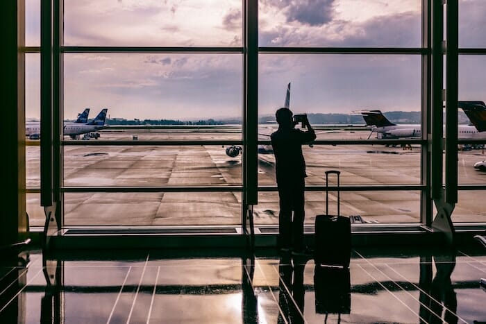 person taking a picture of a plane at an airport window