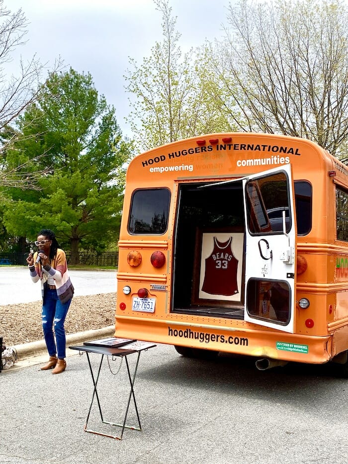 Hood Huggers International tour bus next to a street performer